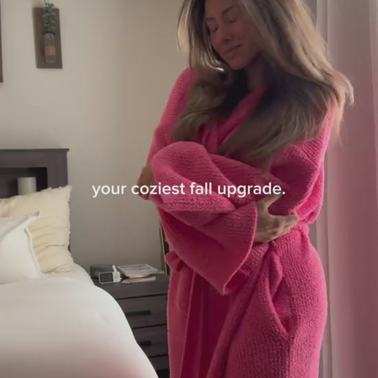 Woman wrapping herself in the long robe in Salmon in her bedroom