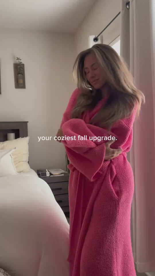 Woman wrapping herself in the long robe in Salmon in her bedroom